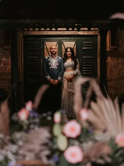 A beautifully framed shot of the couple, seen through a foreground of delicate flowers, adding depth and romance to their portrait.
