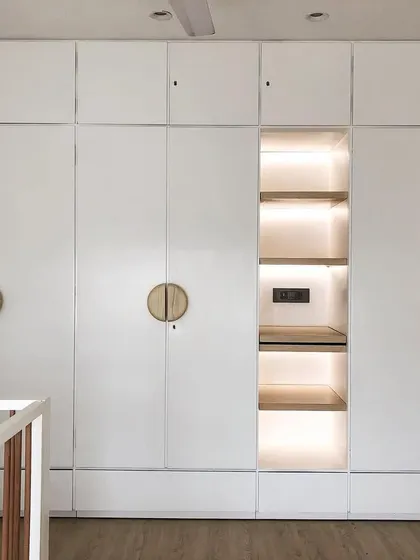 This custom white wardrobe features a lit-up central niche, perfect for displaying special items or for use as a small changing station. The round wooden handles add a soft, modern touch.