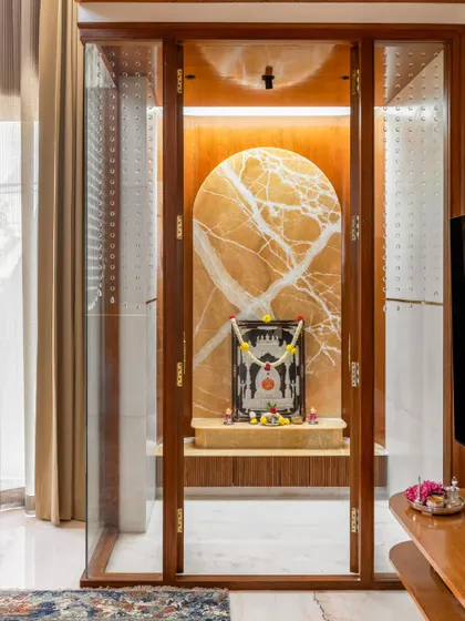 We integrated this tranquil pooja room into the main living area of the Avani Residence. Encased in glass and wood, the space features a monolithic onyx stone backdrop illuminated by a skylight, creating a serene and spiritual focal point.