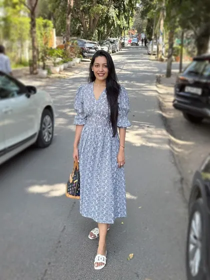 This client is wearing an easy, breezy, and chic Schiffli summer dress in a lovely blue and white print. With its comfortable fit and puff sleeves, it's the perfect go-to dress for a sunny day.