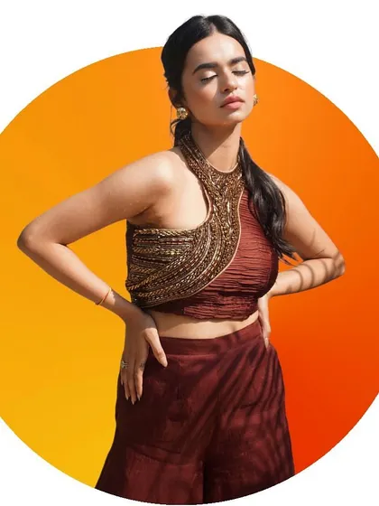A confident pose showcasing the unique design of the halter-neck crop top. The warm, circular background makes this a perfect shot for a summer collection campaign.