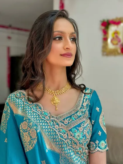 A beautiful look for a 'Grah Pravesh' ceremony, featuring a teal outfit and soft, warm-toned makeup.