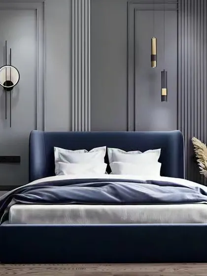 A chic and modern bedroom with a deep blue upholstered bed set against a grey paneled wall with minimalist pendant lights.