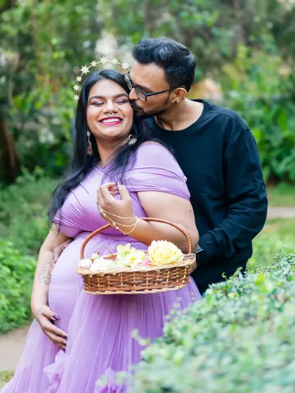 A sweet kiss on the cheek for the glowing mother-to-be. Her beautiful smile, combined with the soft lighting and flower crown, makes this a truly radiant maternity portrait.