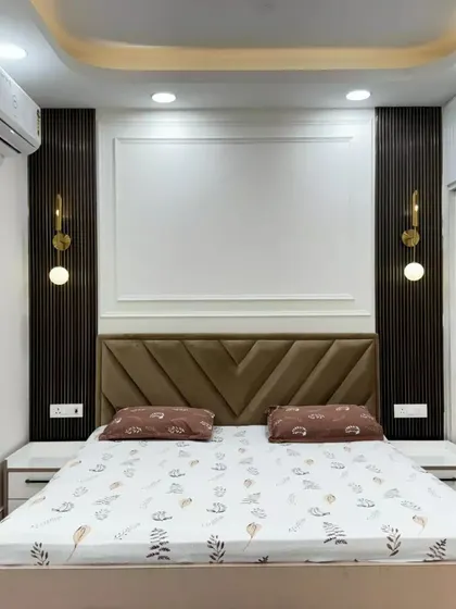 A completed bedroom project featuring a modern upholstered headboard, stylish wall sconces, and clean lines for a contemporary and comfortable sleeping space.