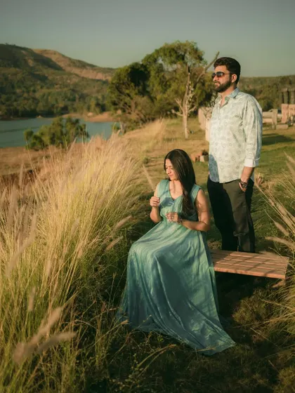 A couple enjoying a peaceful moment in a field of tall grass, with a beautiful lake and hills in the background. A perfect destination pre-wedding shot.