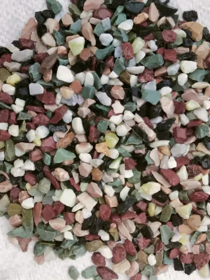A mix of colorful unpolished pebbles, including green, red, yellow, and white.