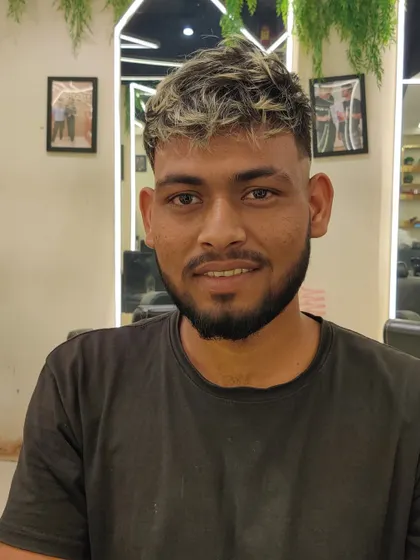 A smiling client with his new haircut, featuring a clean fade and a stylishly messy, highlighted top.