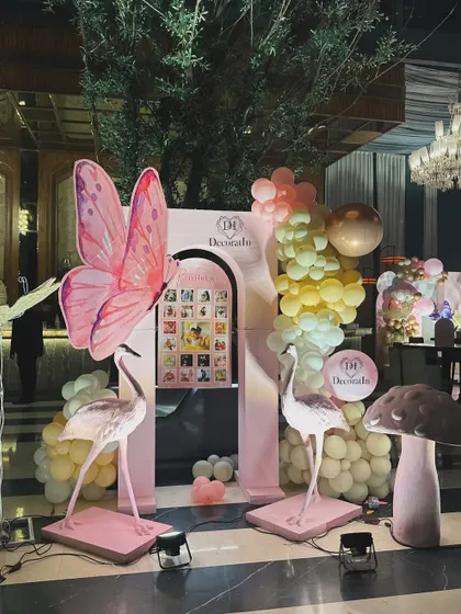 The memory lane photo display, complete with flamingo props, a giant butterfly, and a whimsical mushroom, creating a fairytale corner.