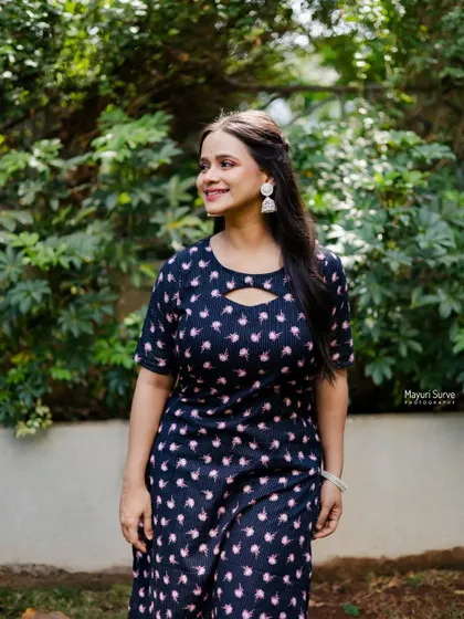 A candid and happy outdoor portrait. The model, dressed in a comfortable printed kurta, looks away with a bright smile, creating a warm and natural lifestyle shot.