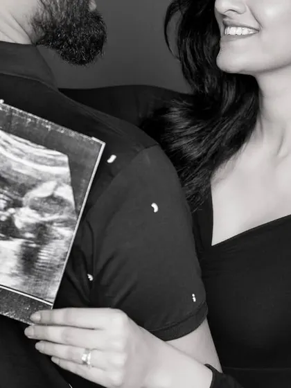 A creative shot showing the ultrasound scan held against the dad-to-be's back, a unique way to announce the pregnancy.