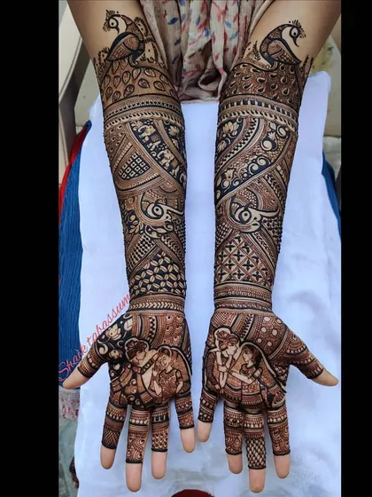 A graceful design featuring swirling peacock motifs that flow from the wrist to the elbow. The palms are reserved for a detailed portrait of the bride and groom, making it the heart of the design.