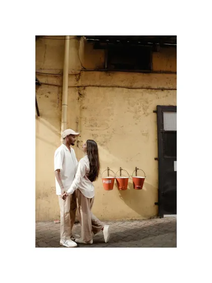 A stylish pre-wedding portrait against a rustic, textured wall, showcasing the couple's modern and relaxed vibe.
