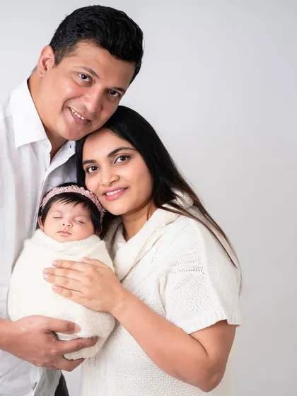 A classic family photo with both parents looking at the camera. This is a timeless shot that every family treasures, a beautiful record of this special time in their lives.