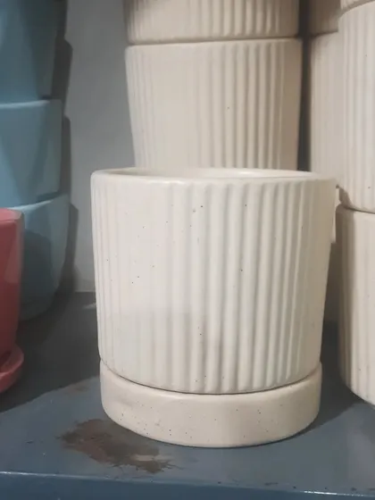 A classic, ribbed ceramic planter with an attached saucer. This timeless design in a neutral off-white color fits well with any interior style, from modern to traditional.