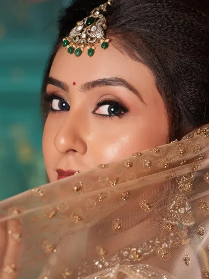 A peek-a-boo shot highlighting the beautiful maang tikka with green stones.