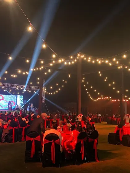 The full view of a lively sangeet night in Lonavala. We set up a large stage with an LED screen for performances and arranged round tables for guests, with string lights overhead creating a festive canopy.