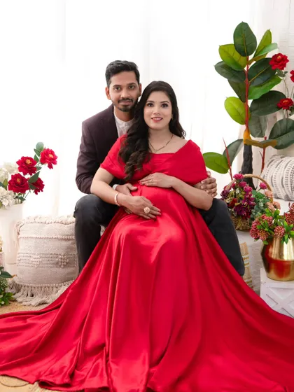 Seated together in a romantic, floral-adorned setting, this couple radiates happiness. The vibrant red of her gown symbolizes the love and passion of this new chapter.