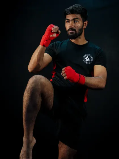 The classic kickboxing stance, with hands up and a knee raised, ready to strike or defend. We teach the fundamentals that win fights.