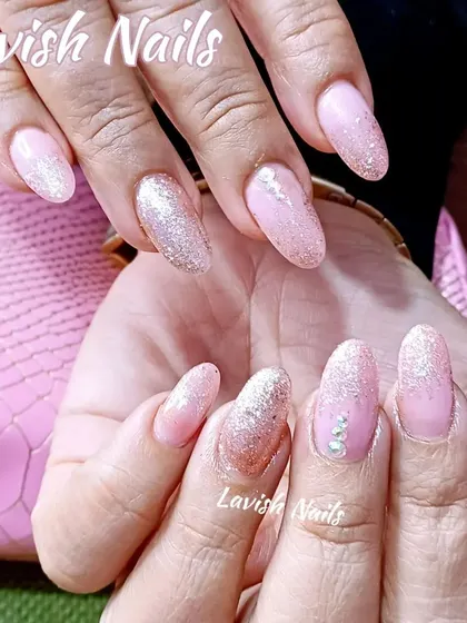Soft pink almond nails with a gentle fade of silver glitter from the tips, accented with a few scattered crystals for extra sparkle.
