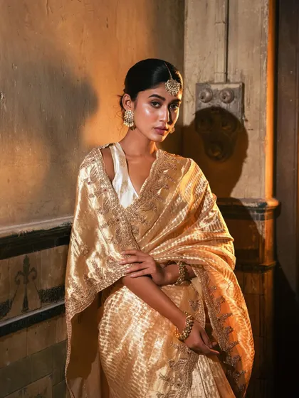 A moment of quiet elegance in a golden tissue saree. The intricate border and the way the fabric catches the light make this a truly special piece. It’s perfect for an evening reception or a formal dinner.