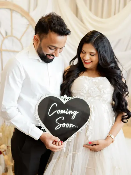 "Coming Soon." This happy couple holds a sign announcing their baby's arrival, their smiles lighting up the frame.