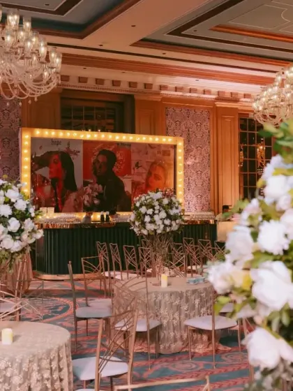 A view of the sangeet ballroom showing the main bar, which features a large, backlit frame with the couple's pre-wedding shoot photos.