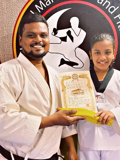 This student proudly holds her new yellow belt and certificate, ready for the next stage of her Taekwondo training.