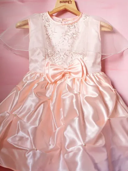 Another view of the peachy-pink bubble dress, showing the sheer capelet sleeves that add a touch of ethereal grace.