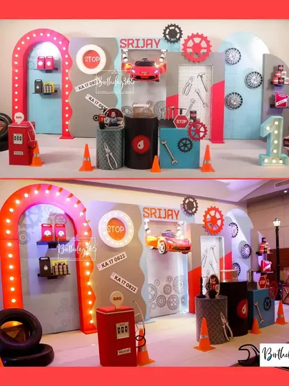 A full view of our mechanic-themed party for Srijay's first birthday. The setup includes a tool-covered backdrop, a light-up gas station arch, and a cool red car prop.