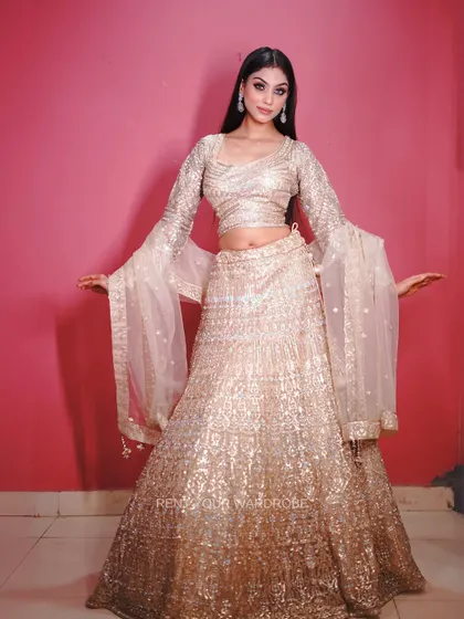A full-length view of our golden sequin lehenga with dramatic bell sleeves, perfect for a glamorous party.