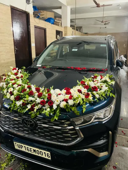 The fully decorated wedding car, ready for the groom to bring his bride home. The floral arrangement on the hood is lush and elegant.