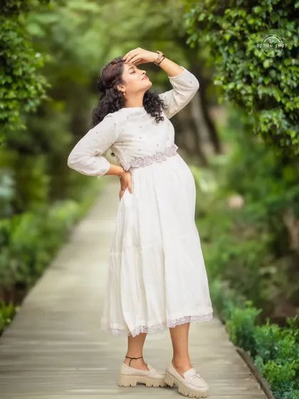 A beautiful solo outdoor portrait, with the mom-to-be basking in the sunlight in a lovely white traditional dress.
