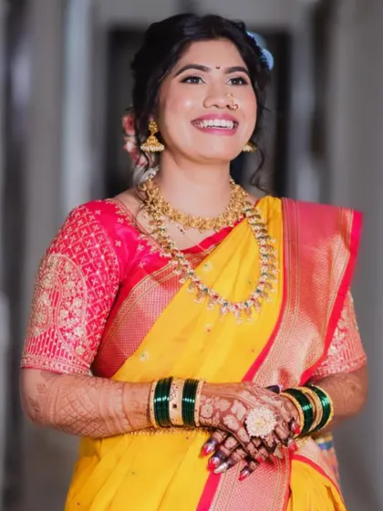 A happy bride in a yellow saree. The makeup is fresh and glowing, with a simple hairstyle adorned with flowers.