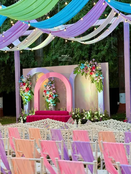 A pastel-themed stage with a bright pink sofa, framed by arches and floral arrangements.
