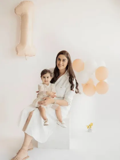 A mother and daughter celebrating a first birthday. This simple, elegant portrait in all-white outfits is a beautiful way to mark a special milestone together.