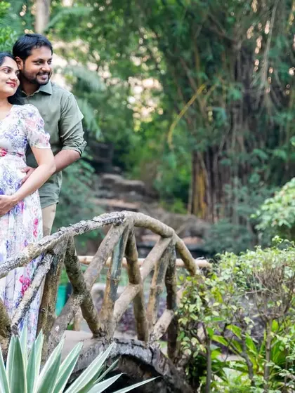 A wide shot that captures the couple on a bridge, surrounded by the beauty of the park. It tells a story of their journey together in a serene and picturesque setting.
