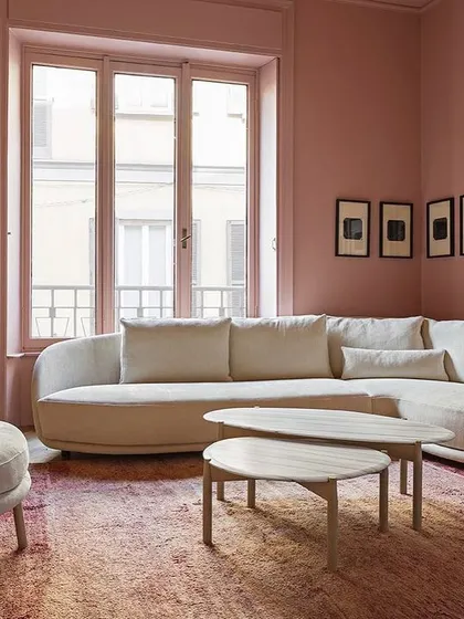 This living room setup features a gently curved sofa and a matching armchair in a soft, neutral fabric. The organic shapes of the furniture create a soothing and welcoming environment, complemented by the warm tones of the room.