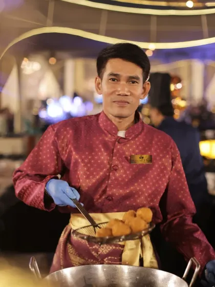 Service with a smile. One of our international chefs proudly presents a batch of freshly fried treats, ready to be served to guests.