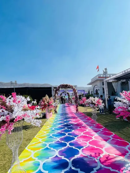 A vibrant, rainbow-colored aisle runner for a Haldi ceremony. This adds a splash of color and fun to the event, leading to a beautiful floral arch.