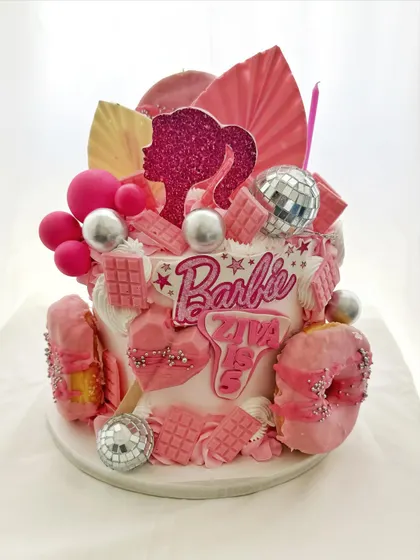 A modern and trendy Barbie cake, featuring a silhouette, disco balls, and geometric chocolate pieces.