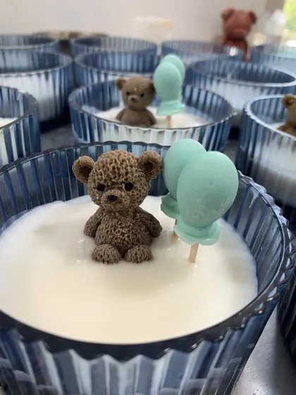 A close-up of the teddy bear baby shower candle. The detail on the knitted texture of the teddy bear is all achieved with wax.