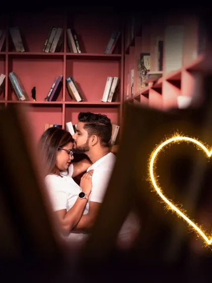 A creative and intimate pre-wedding shot in a library setting. The sparkling heart overlay adds a touch of magic to this romantic moment.