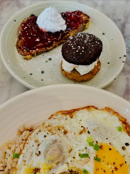 A hearty brunch plate with a sunny-side-up egg over rice and a side of French toast with jam.