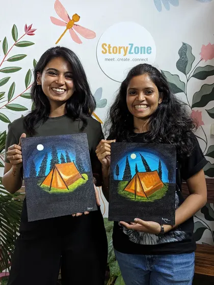 Two friends with their matching camping-themed canvas paintings. A perfect way to create a shared memory.