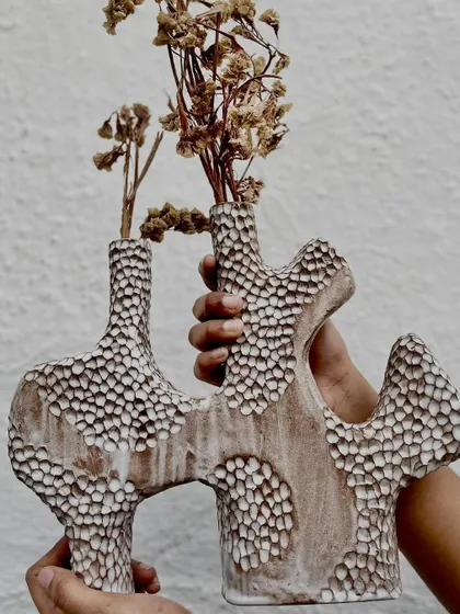 Holding up the finished, unglazed vase. The organic shape and detailed texture make this a true statement piece.