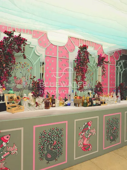 A full view of the beautifully decorated bar, with its pastel green and pink color scheme and intricate folk art patterns.