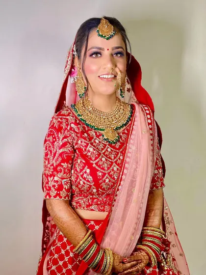 A beautiful bride in red with a soft pink dupatta. The makeup is fresh and dewy, perfect for her daytime ceremony.