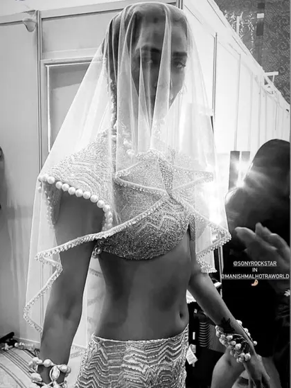 A black and white shot from backstage at the Manish Malhotra show, capturing the artistic detail of the modern veil and bridal outfit. The makeup underneath was kept clean and radiant.