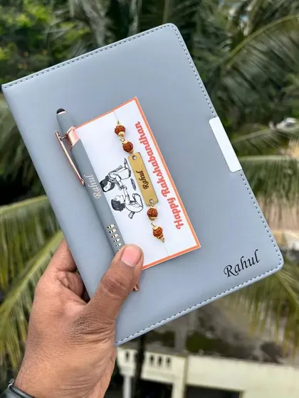 A thoughtful Rakhi gift set including a personalized diary and pen, along with a custom name rakhi.